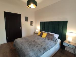 a bedroom with a large bed with a green headboard at Apartament MilioNova in Łódź