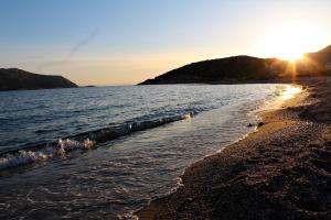 a beach with the sun rising over the water at Helen's Sounio Apartments in Sounio
