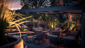 une terrasse avec des chaises, des tables et des fleurs dans l'établissement Le Parc Hôtel Obernai & Yonaguni Spa, à Obernai