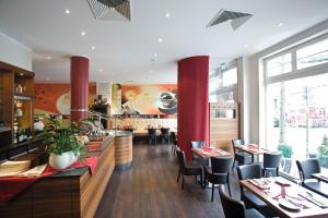 a restaurant with red pillars and tables and chairs at Hotel Gräfrather Hof in Solingen