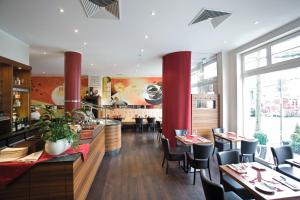 een restaurant met rode pilaren en tafels en stoelen bij Hotel Gräfrather Hof in Solingen