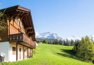 a house on a hill with mountains in the background at Chalet Irene in Wengen