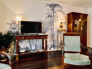 - un salon avec une télévision sur un mur orné de palmiers dans l'établissement Le Jardin Kerveguen, calme, confort et déco unique, Mer à 8 min, St Pierre-Tampon 400, à Le Tampon