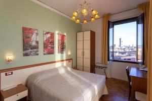 a bedroom with a bed and a desk and a window at Soggiorno Rubino in Florence