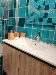 a bathroom with a sink and a blue tiled wall at Magnifique deux pièces au calme in Deauville