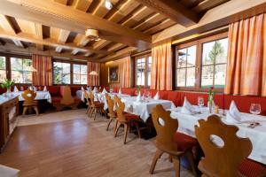 un restaurante con mesas y sillas blancas y ventanas en Bruggerhof - Camping, Restaurant, Hotel en Kitzbühel