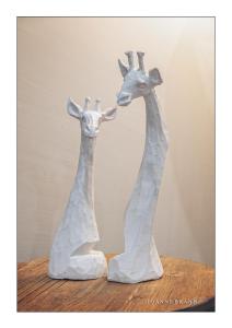 two giraffes sculptures sitting on a wooden table at Felzarette Self Catering Apartment 7 in Windhoek