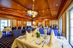 une salle de banquet avec des tables et des chaises ainsi qu'un lustre dans l'établissement Hotel Landhaus Krombach, à Elkenroth