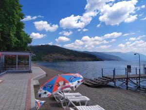 a beach with chairs and an umbrella next to the water at Villa Ivanovi in Ohrid