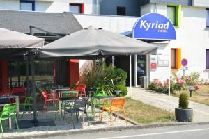 um restaurante com mesas e cadeiras e um guarda-sol em Kyriad Rennes Sud - Cesson Chantepie em Chantepie