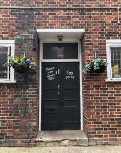 a black door in a brick building with two windows at The Queens Hostel in London