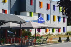 un grupo de mesas con sombrillas frente a un edificio en Kyriad Rennes Sud - Cesson Chantepie, en Chantepie