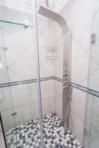 a shower with a glass door and a checkered floor at Van Den Berg's Guesthouse in Bettyʼs Bay