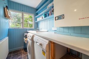 a kitchen with blue walls and a white counter top at Cob Cottage in St. Agnes