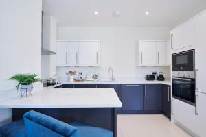 a kitchen with white cabinets and a blue chair at Palace Wharf in London