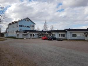 a large white building with cars parked in a parking lot at Maaseutuhotelli Hirvikoski in Sykäräinen