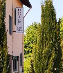 un panneau sur le côté d'un bâtiment avec des arbres dans l'établissement Hotel Köln-Bonn, à Bornheim