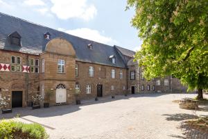 ein großes Backsteingebäude mit großer Auffahrt in der Unterkunft Hotel am Schloss Broich in Mülheim an der Ruhr