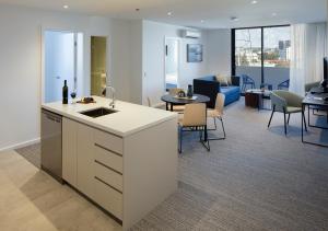 a kitchen with a sink and a living room at Quest Robina in Gold Coast