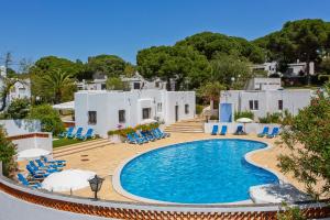 a pool in front of a house with blue chairs at Prado do Golf in Vilamoura