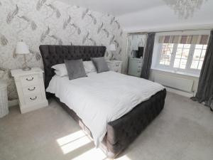 a bedroom with a large bed with white sheets at Farriers Cottage in Lincoln