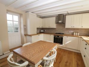 a kitchen with a wooden table and white cabinets at Farriers Cottage in Lincoln