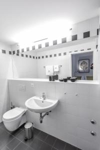 a white bathroom with a toilet and a sink at Villa Muralto Rooms & Garden in Locarno