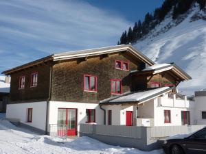 a house in the snow with red windows at Haus Emilia am Faschinajoch in Fontanella