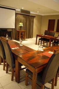 a conference room with wooden tables and chairs and a screen at Afrique Boutique Ruimsig in Roodepoort