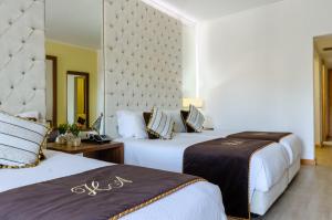 a hotel room with two beds and a wall at Hotel Alvorada in Estoril