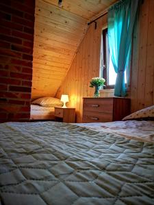 a bedroom with a bed and a window with blue curtains at Domki Zielony Winiec - Mazury in Winiec