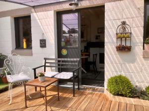 eine Veranda mit einer Bank auf einer Holzterrasse in der Unterkunft Le grenier du jardin in Pontorson