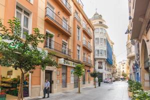 una calle de la ciudad con edificios y un hombre de pie en la acera en TGH/ En el corazón de Málaga - Sebastian Souviron, en Málaga