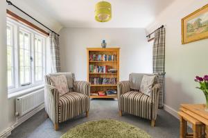 a living room with two chairs and a book shelf at Crow Cottage by Bloom Stays in Faversham