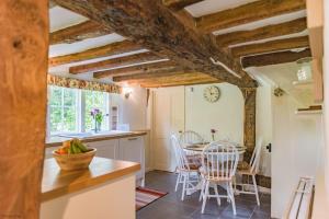 uma cozinha com tectos em madeira e uma mesa com cadeiras em Walnut Tree Cottage by Bloom Stays em Faversham