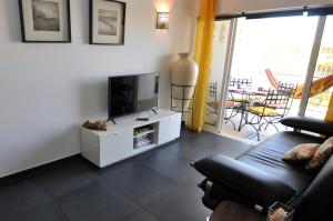 een woonkamer met een flatscreen-tv en een bank bij Sea and Pool at Vila da Praia in Alvor
