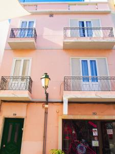 ein rosafarbenes Gebäude mit Balkon und Straßenbeleuchtung in der Unterkunft Alagoa Terrace Guesthouse in Faro