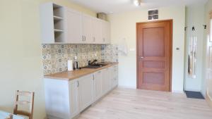 une cuisine avec des placards blancs et une porte marron dans l'établissement Apartament Hanka, à Krościenko nad Dunajcem