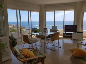 een woonkamer met een tafel en stoelen en de oceaan bij The Sunrise of your Dreams with Total Ocean View in Funchal