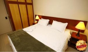 a bedroom with a large white bed with two lamps at London Class Hotéis in Sao Paulo