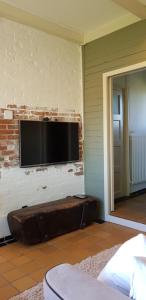 een woonkamer met een televisie aan een bakstenen muur bij Gastenverblijf Goudswaard in Goudswaard