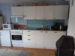 a kitchen with white cabinets and a white stove top oven at Kesäranta in Tynkä