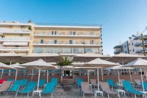 een rij stoelen en parasols voor een gebouw bij Hotel Ostria in Kalamata