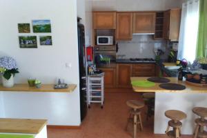 cocina con armarios de madera y encimera en Hilltop Azores - Beach & Countryside, en Porto Formoso