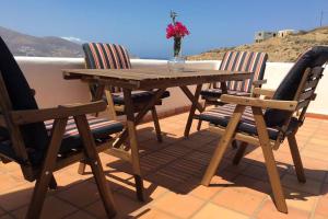 un tavolo in legno con due sedie e un vaso con fiori di Ftelia Panoramic Sea View Villa Aias a Ftelia