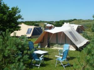 a group of chairs and tents in a field at Ameland Tentenverhuur in Nes +19 photos