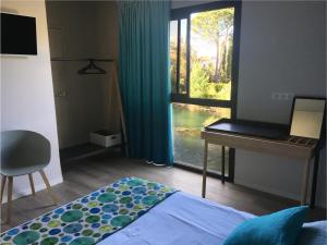 una camera con letto, scrivania e finestra di Hotel Cantosorgue a LʼIsle-sur-la-Sorgue