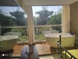 Baño con 2 bañeras frente a una ventana en Loft Espaço Vila da Serra, en Nova Lima