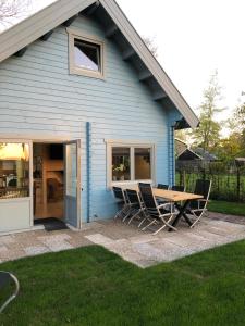 a table and chairs in front of a blue house at Vakantiewoning Vrijburg in Schagerbrug