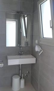 a bathroom with a sink and a mirror and a toilet at Nasos Hotel & Resort in Moraitika